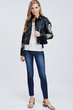 full body view of faux leather jacket with embroidered sleeves. meets at your waist. zip up in front and tie around waist