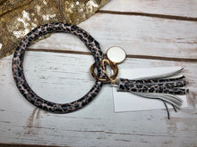 small print leopard animal print with white background bangle ring keychair with tassle and monogram tag. large ring for any size wrist and easy clip for attaching keys. contains two 2 rings to attach keys to. leopard print, animal print, cute, and fun.