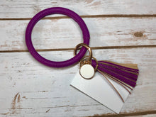 purple bangle ring keychair with tassle and monogram tag. large ring for any size wrist and easy clip for attaching keys. contains two 2 rings to attach keys to. monochromatic, cute, and fun.