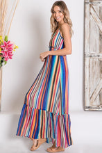 side view of mulit-color stripe serape maxi with adjustable spaghetti strapes, smocked waist, and ruffle hem