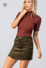olive green colored corduroy mini skirt with a zipper fly. equipped with belt loops and pockets. frayed hem on the bottom