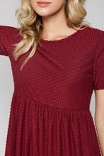 up close view of detail on short sleeve burgundy with dot textured short dress that goes to knees. cinches at the small of the waist and flows out tiered on the bottom half