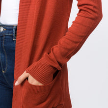 zoomed in picture of rust colored soft and cozy cardigan with pockets. long sleeve and in between knee and butt length