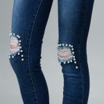 up close view of pearl distressed jeans. blue jeans with distressed knees lined with pearls. for that comfy and classy look