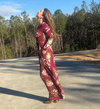side view of long sleeve burgundy and floral long mazi dress. super soft and stretchy material cinched at the small of your waist. beautiful eye catching burgundy color. and has pockets 