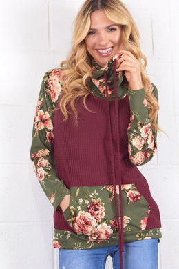 burgendy and olive floral long sleeve top. Sleeves, loose neckline, and front pouch are olive green with floral accent