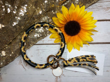 sunflower print with black background bangle ring keychair with tassle and monogram tag. large ring for any size wrist and easy clip for attaching keys. contains two 2 rings to attach keys to. sunflowers, black and yellow, cute, and fun.