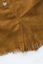 up close view of camel colored corduroy mini skirt with a zipper fly. equipped with belt loops and pockets. frayed hem on the bottom