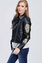 side view of faux leather jacket with embroidered sleeves. meets at your waist. zip up in front and tie around waist