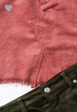 up close view of details on blush pink colored corduroy mini skirt with a zipper fly. equipped with belt loops and pockets. frayed hem on the bottom