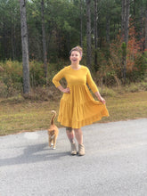 short sleeve mustard with dot textured short dress that goes to knees. cinches at the small of the waist and flows out tiered on the bottom half