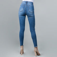back view of blue high rise skinny jeans with stretch. fully embellished in silver and white pearls down to fray hem detail